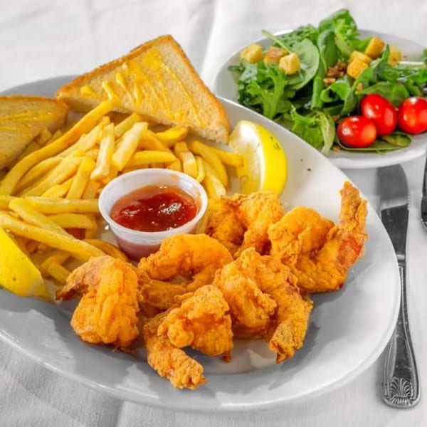 Le Roux's fried shrimp platter with fries, Texas toast, cocktail sauce, lemon, and a side salad.