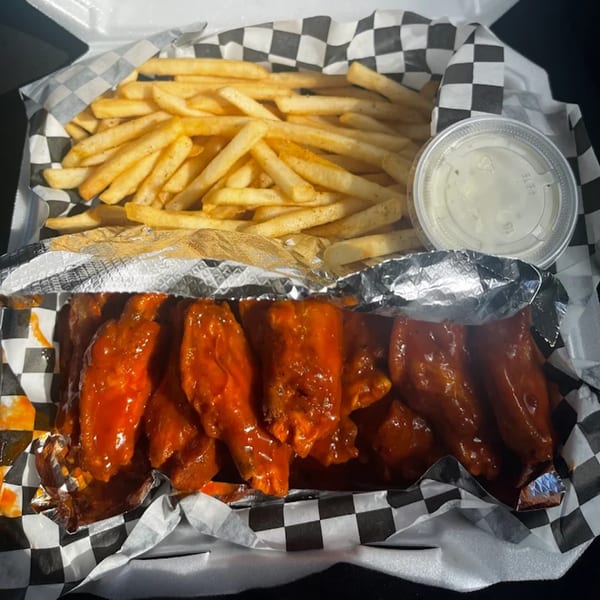Le Roux's Chicken Shack's buffalo wings and fries in a takeout container with ranch dressing.